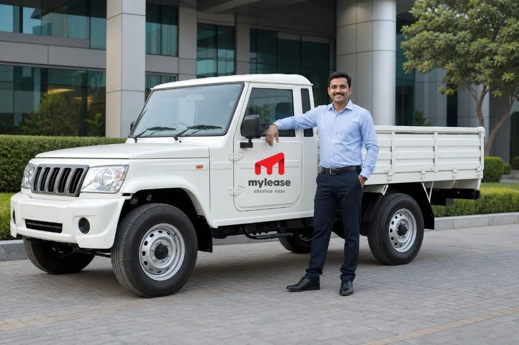 Indian field employee beside a Mahindra Bolero pickup branded with the MYLEASE logo